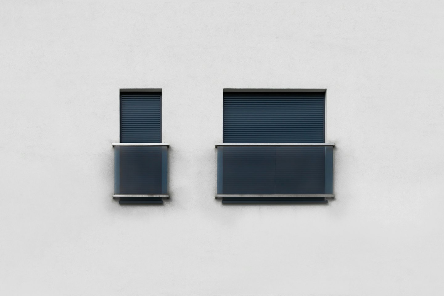 Moderne Gebäudefassade mit dunkelblauen Fensterläden und Glasbalkonen.