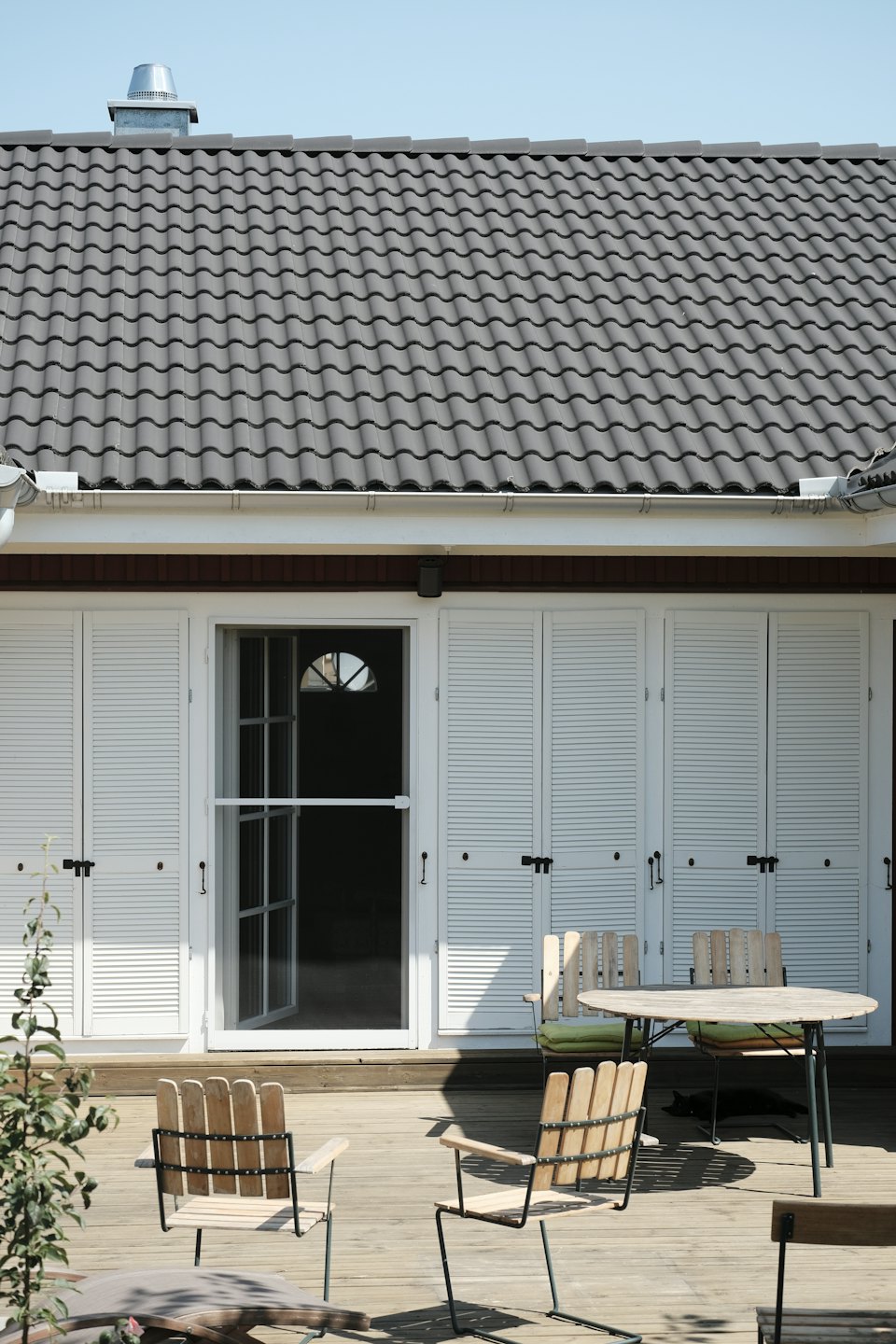 Modernes Haus mit Holzdeck und Terrassenmöbeln.